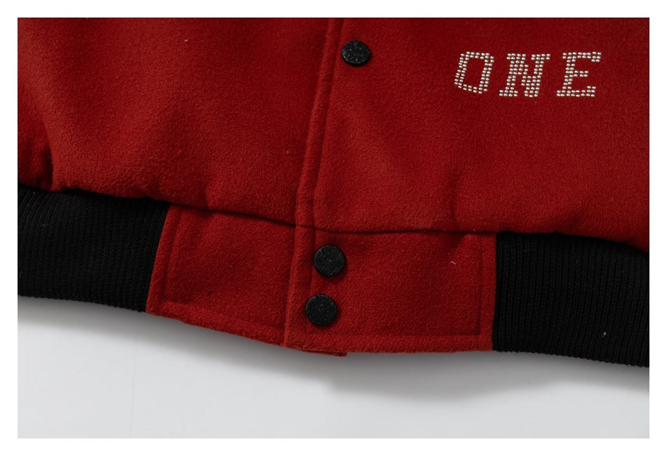 Close-up of a red jacket hem with black ribbed trim, black snaps, and rhinestone text reading “ONE.”