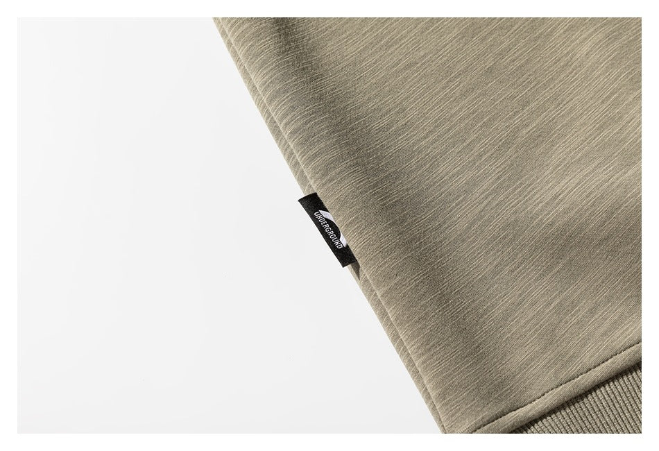 Close-up of the olive-gray sweatshirt fabric and a small black woven side tag.