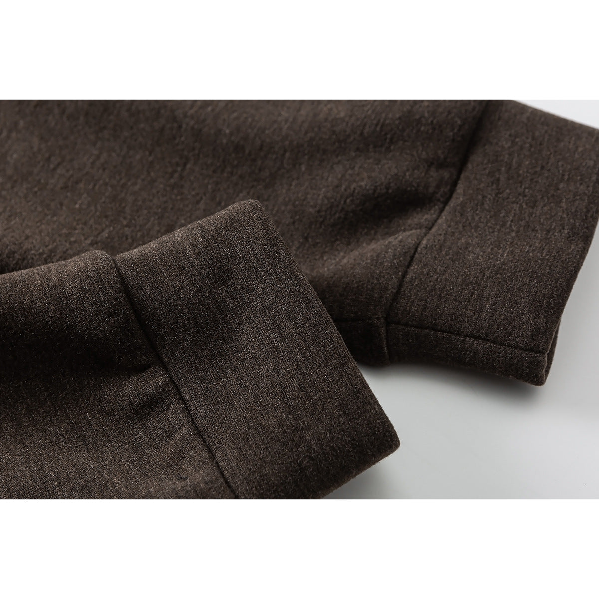 Close-up of the dark brown pullover's sleeve cuff and stitched seam.