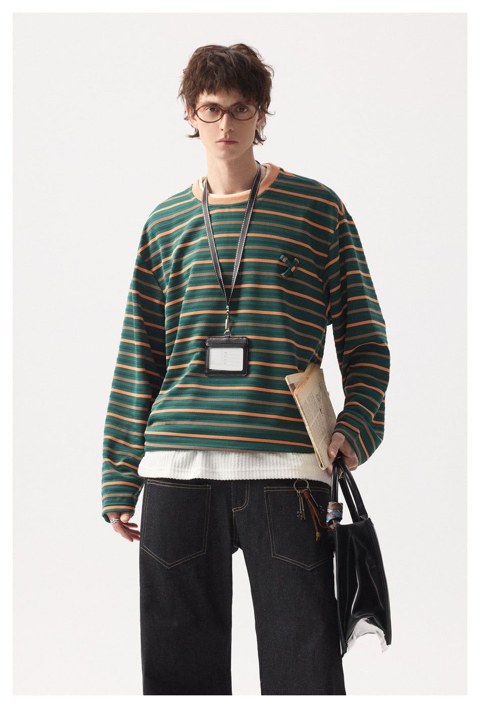 Close view of a person wearing a green and orange striped crew neck top with a layered white inner hem and ID lanyard