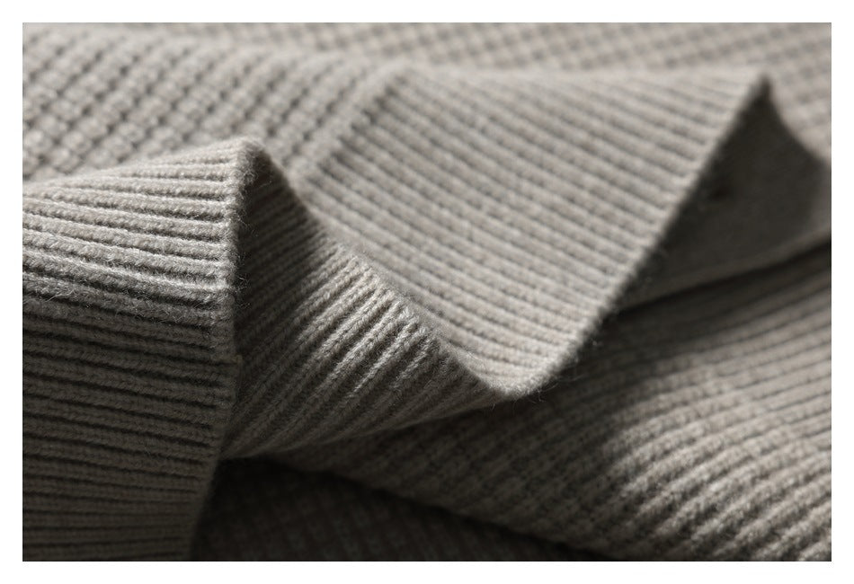 Close-up of the light gray knit garment's thick ribbed edge and textured knit surface.