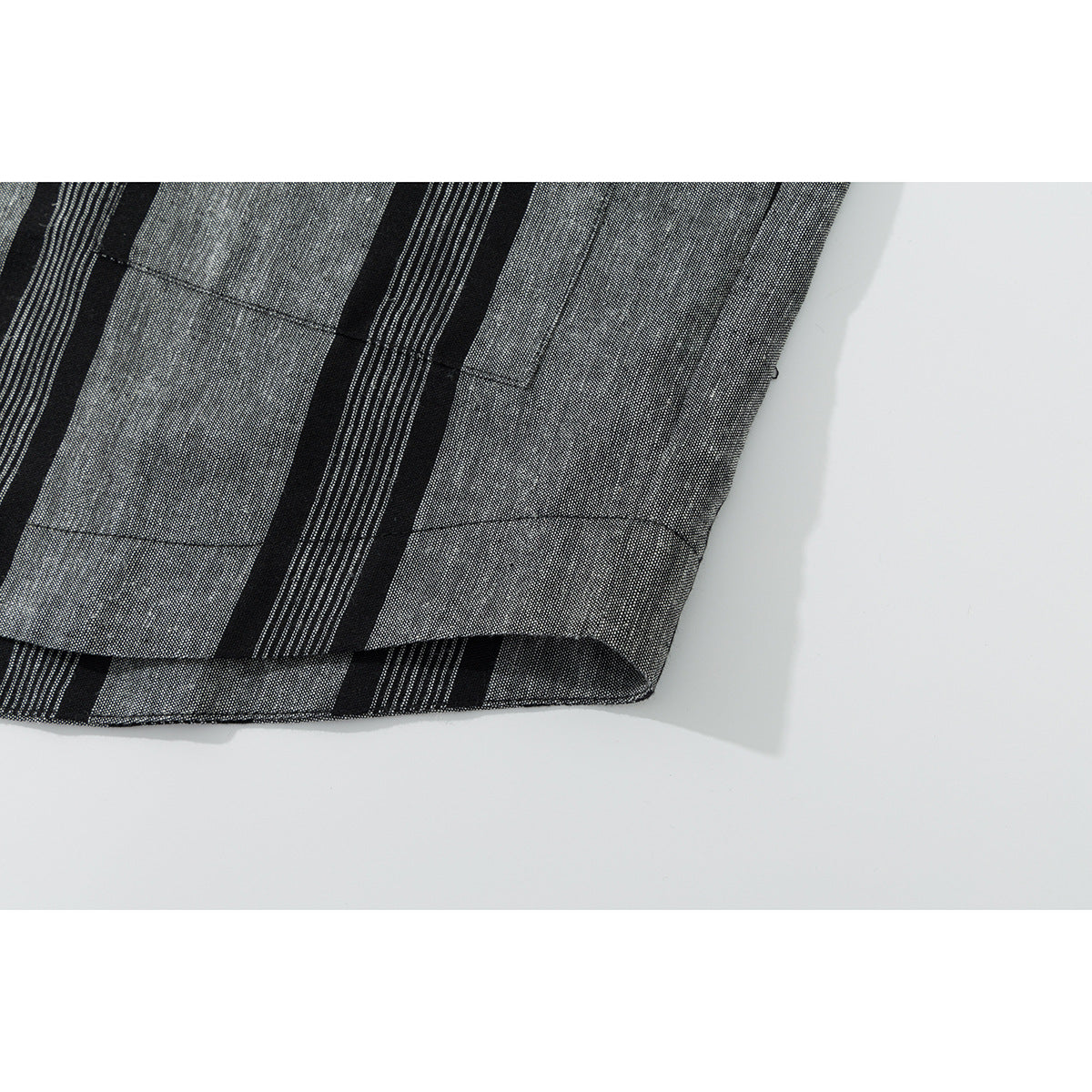 Close-up of the hem and stitching on black and gray striped shirt fabric.