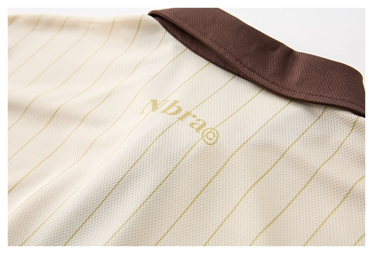 Close-up of the cream pinstriped garment's brown collar and small gold chest mark.