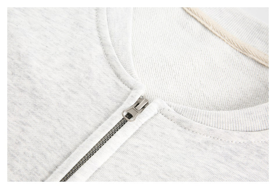 Close-up of the metal zipper and ribbed collar on a light gray sweatshirt.