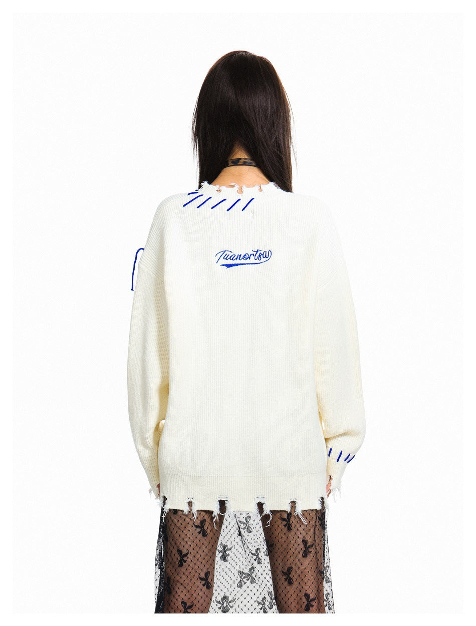 Back view of an ivory distressed sweater with blue stitching and small blue script embroidery across the upper back.