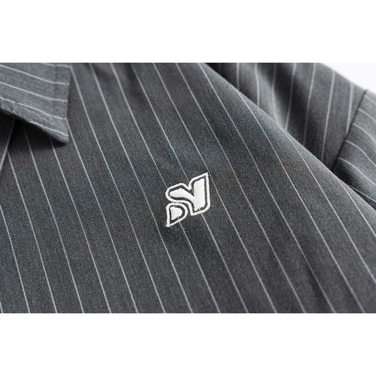 White embroidered emblem on charcoal fabric with thin light pinstripes.