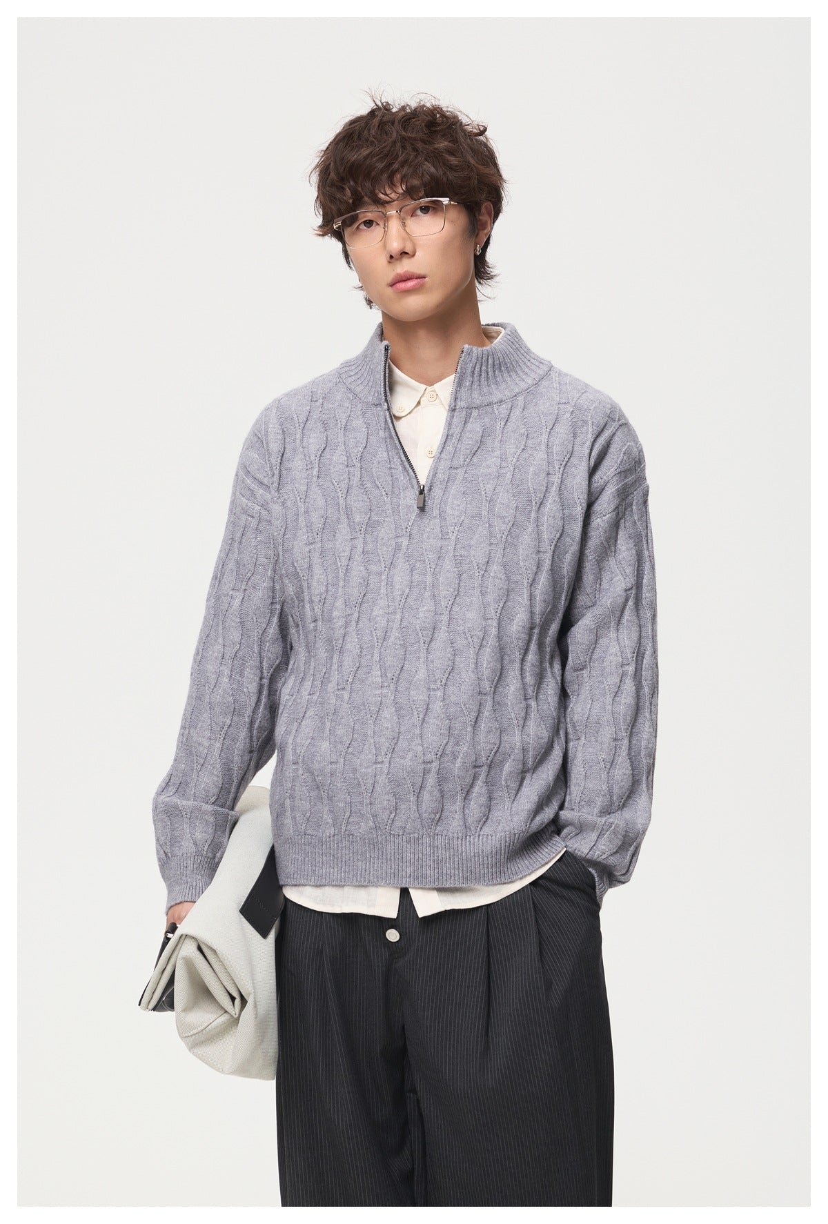 Front upper-body view of a model wearing a light gray cable-pattern quarter-zip sweater.