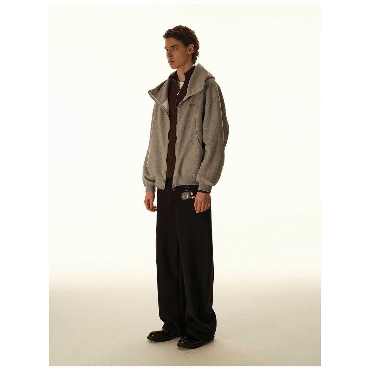Full-length model wearing a loose gray zip-up hooded jacket with black wide-leg trousers.