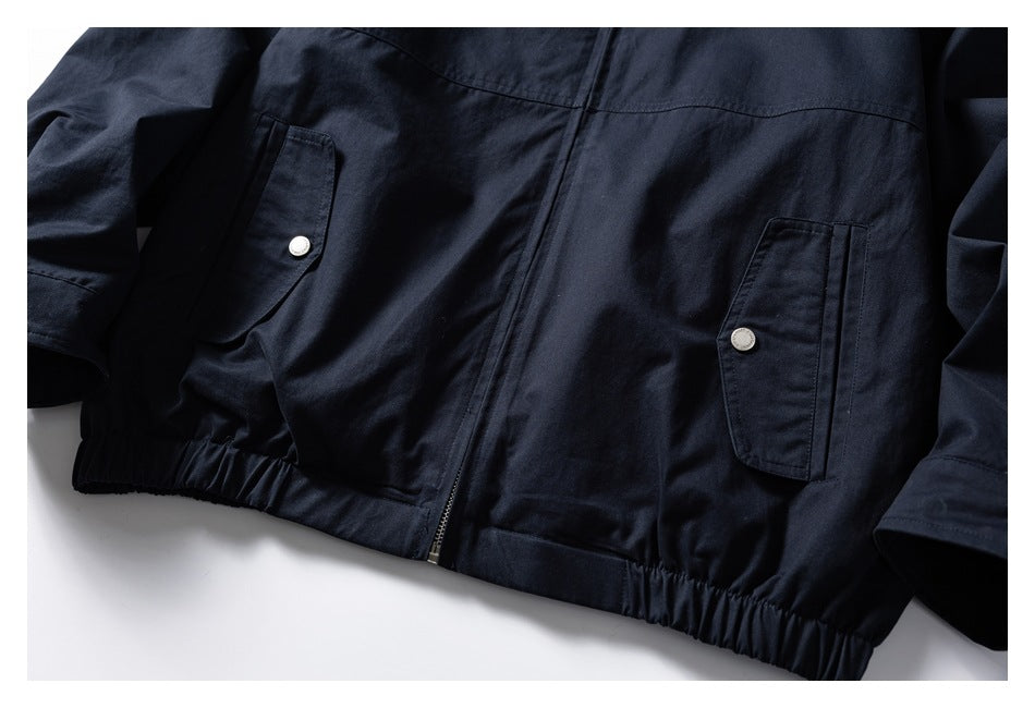 Partial front view of a navy jacket with two snap-flap pockets and a gathered hem.
