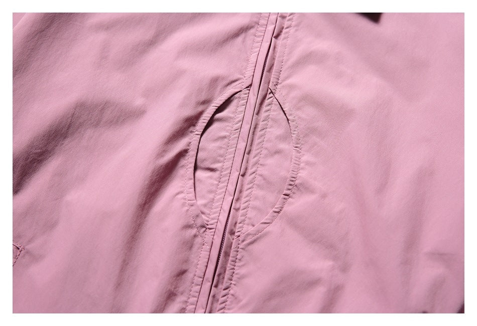 Close-up of the pink jacket's front zipper and curved seam detailing.