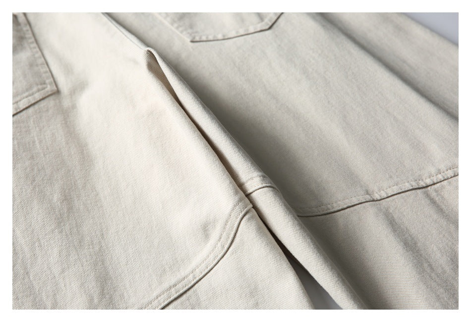Close-up of light beige trousers showing a pocket edge and stitched seams.