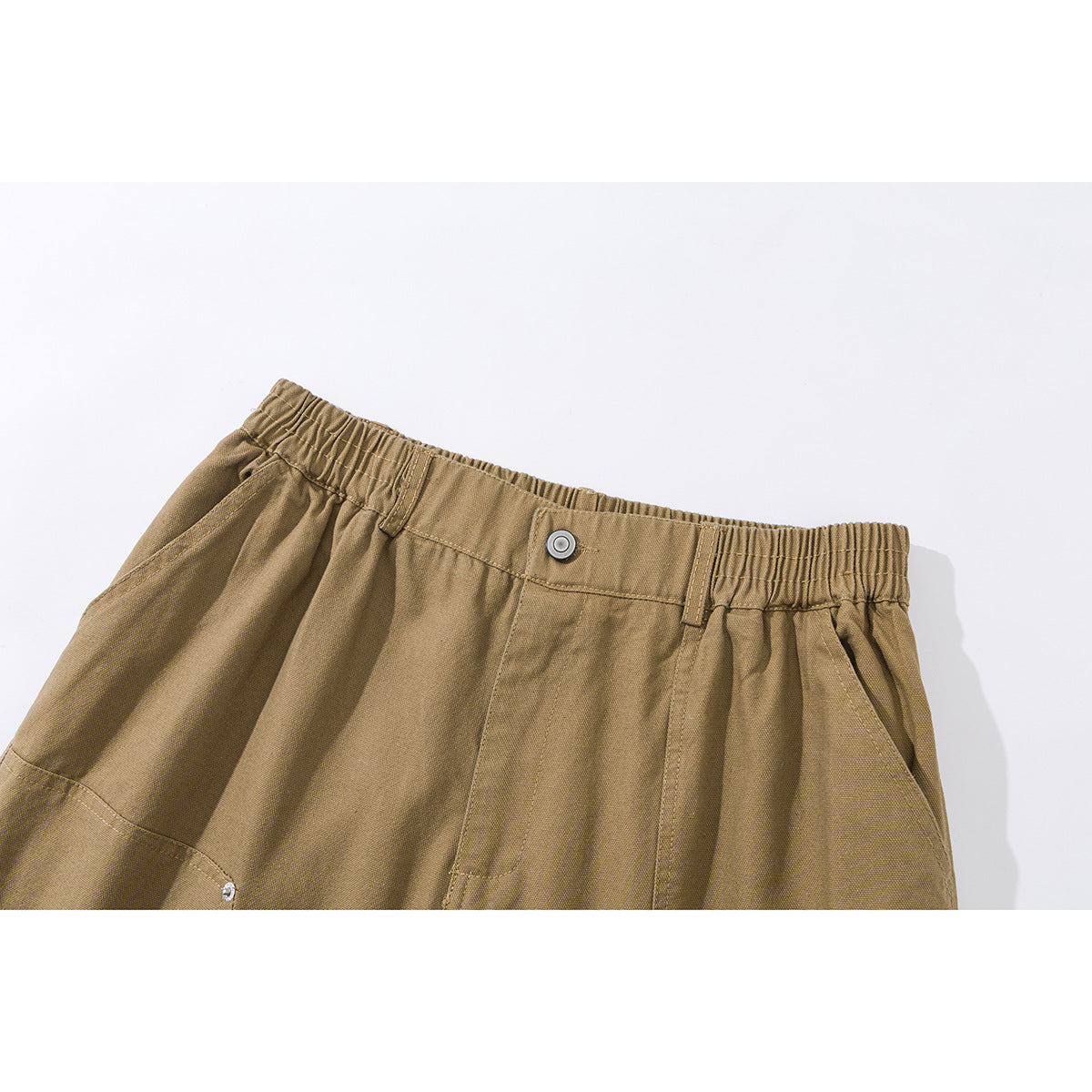 Close-up of tan shorts showing the elastic waistband, button, belt loops, and angled front pockets.