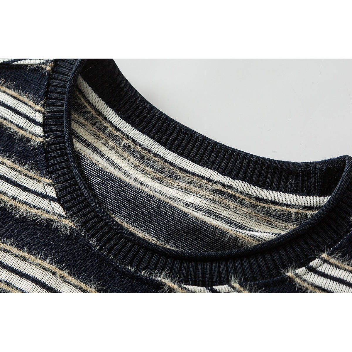 Close-up of a dark crew-neck sweater with ribbed collar and cream, beige, and black horizontal stripes.