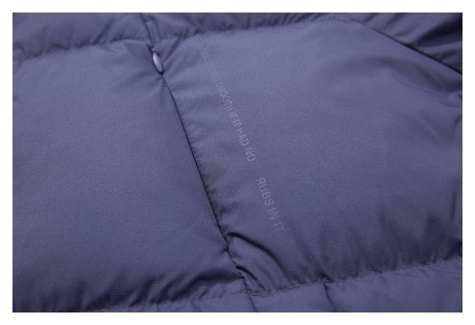 Close-up of a slate-blue padded garment panel with stitched seams, a zipper pull, and faint English text.