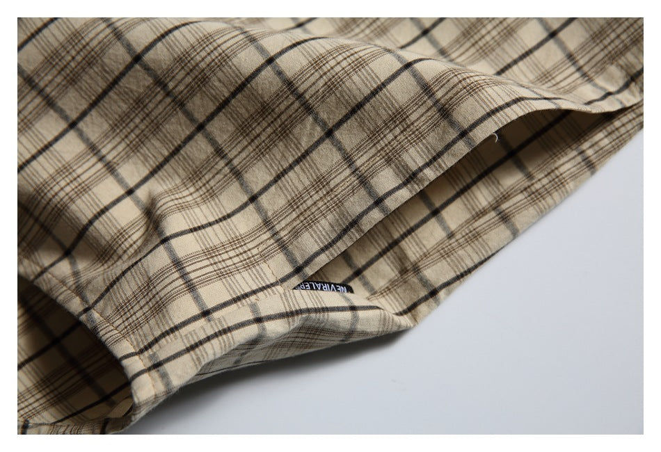 Close-up of the beige plaid shirt hem, with a small black woven label visible underneath.