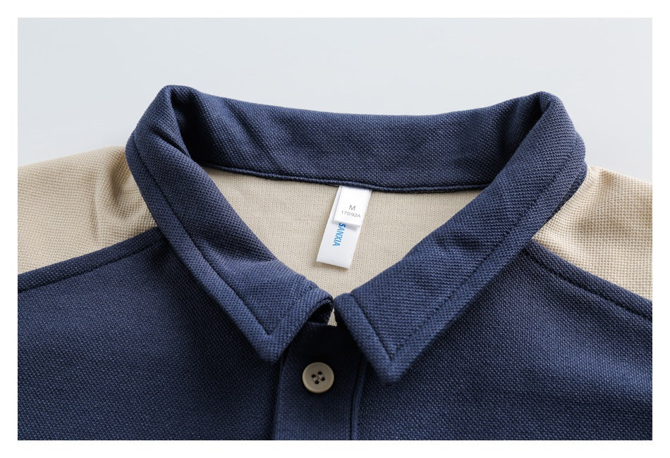 Close-up of a navy polo collar, cream shoulder panels, button, and sewn neck label.