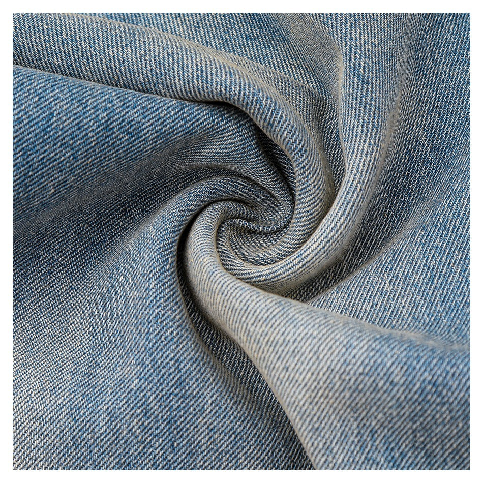 Close-up of blue denim fabric twisted into a spiral fold, showing its woven texture.