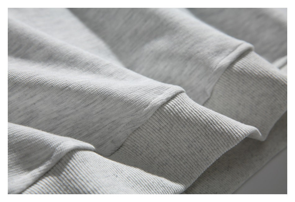 Close-up of the light gray sweatshirt's ribbed hem and folded fabric.