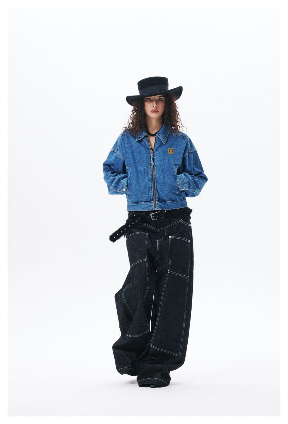 Full-length front view of a model wearing a blue zip-front denim jacket and wide-leg black jeans.
