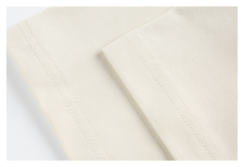 Close-up of cream fabric with parallel rows of stitching along a folded edge.