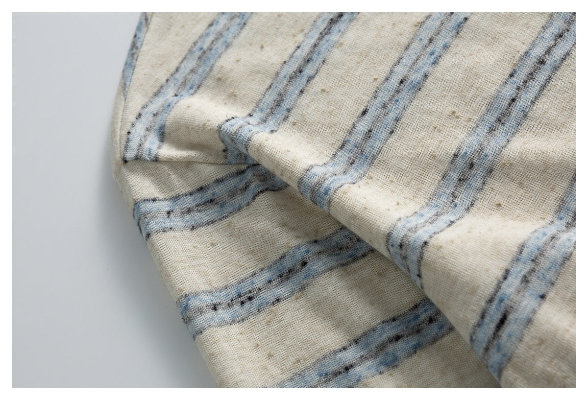 Close-up of cream fabric with irregular blue and charcoal stripes, draped in soft folds.