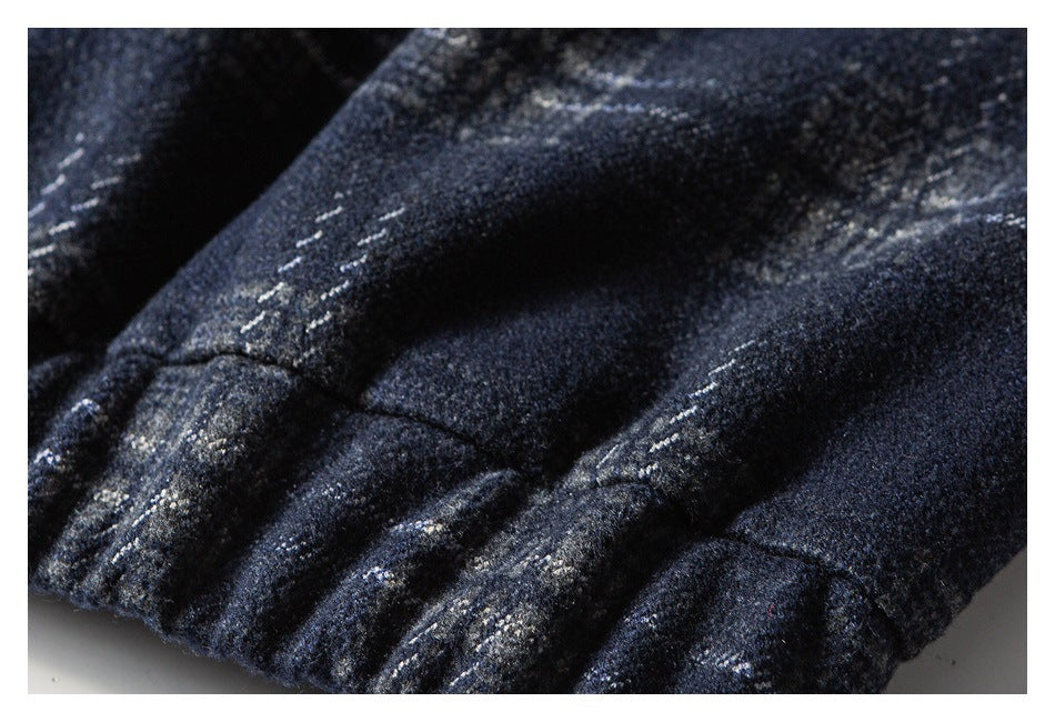 Close-up of a gathered edge and stitching on a dark navy plaid garment.