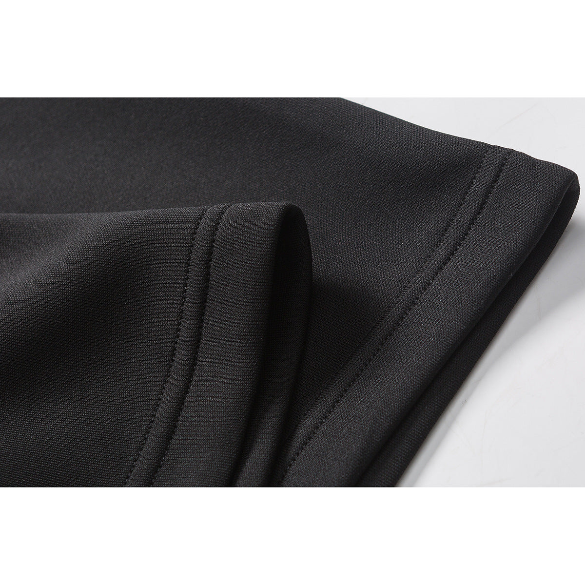 Close-up of the black shirt's stitched sleeve hem and folded fabric edge.