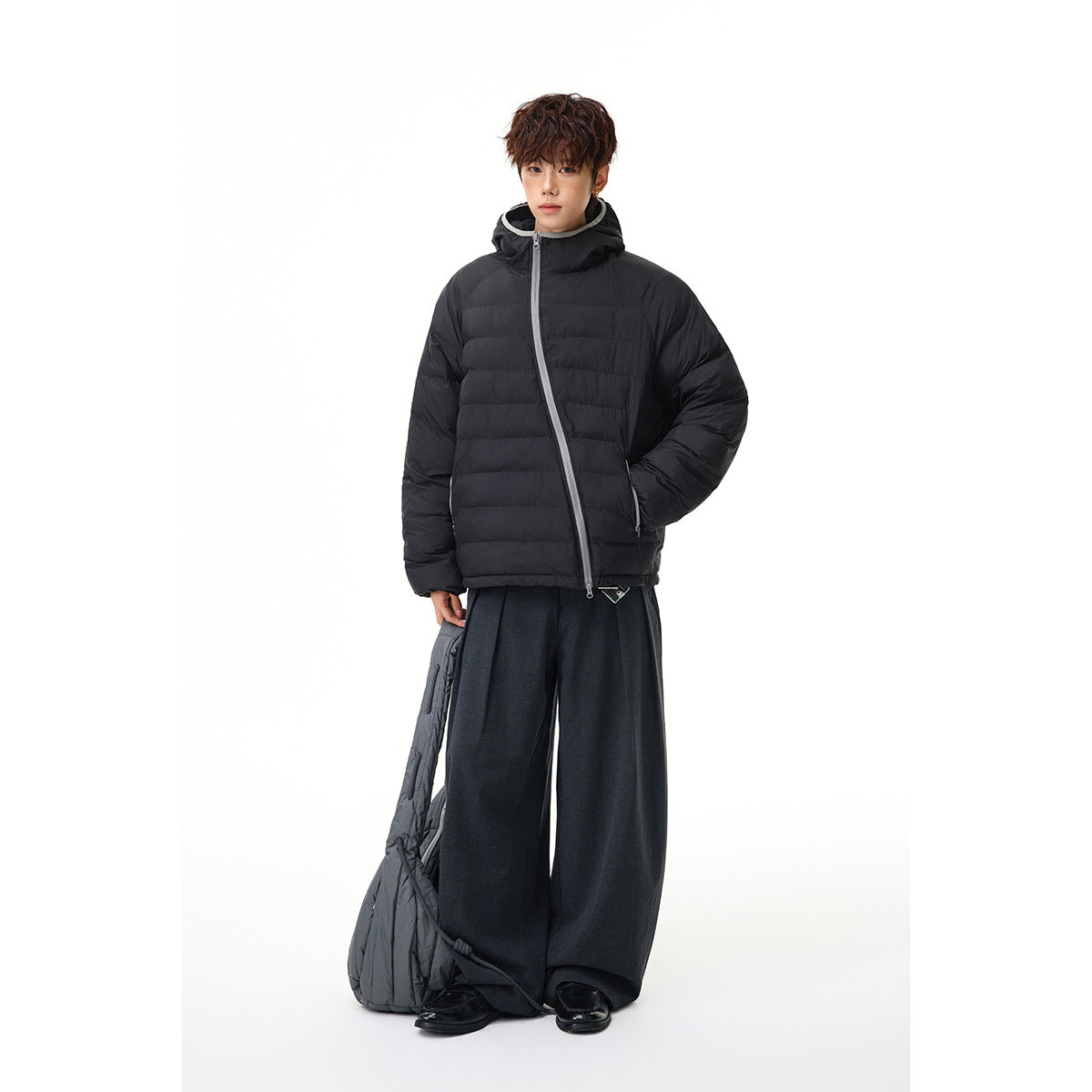 Full-length model wearing a black quilted hooded jacket with gray zipper trim and wide-leg dark trousers.