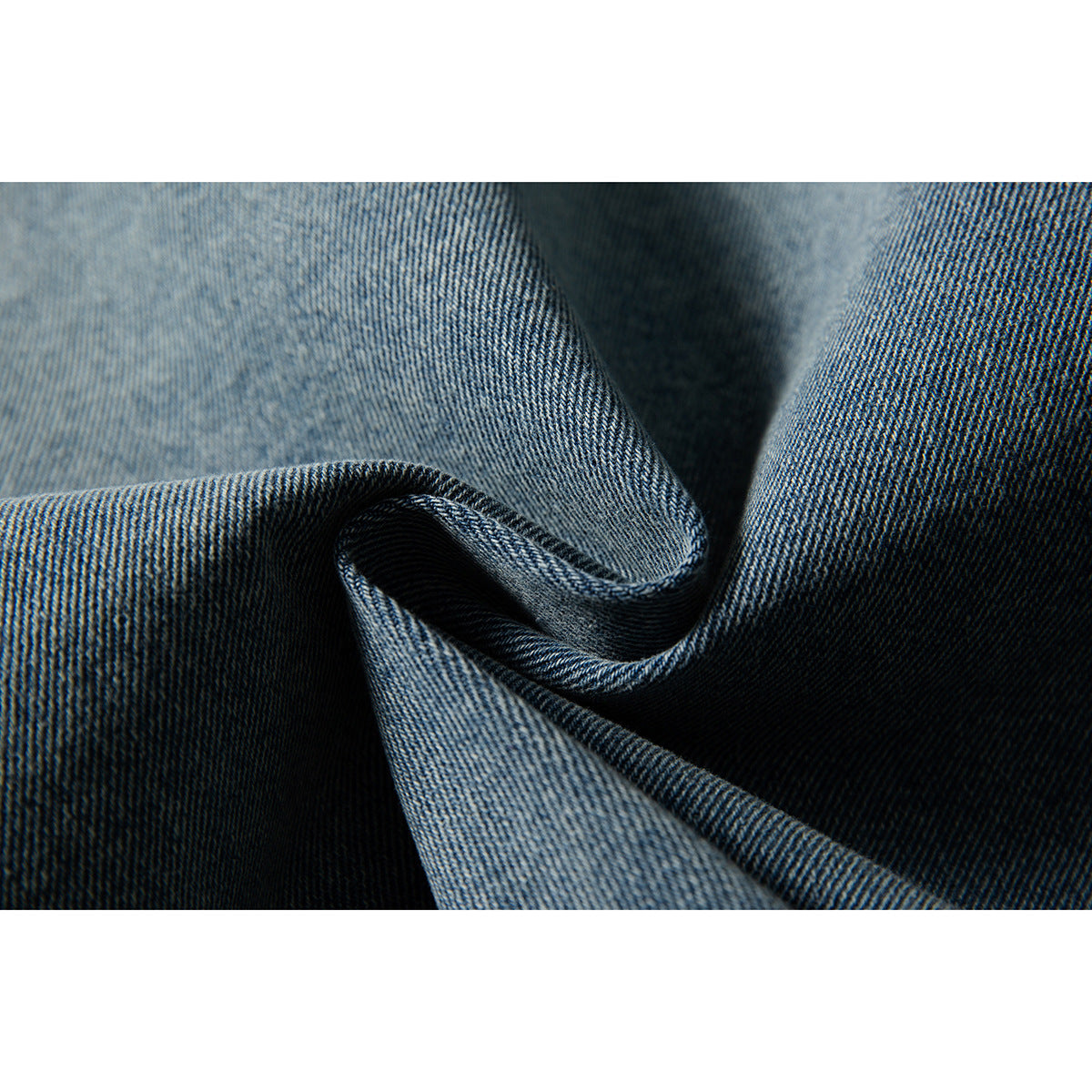 Extreme close-up of blue denim fabric folded to show its diagonal weave and contrasting shades.