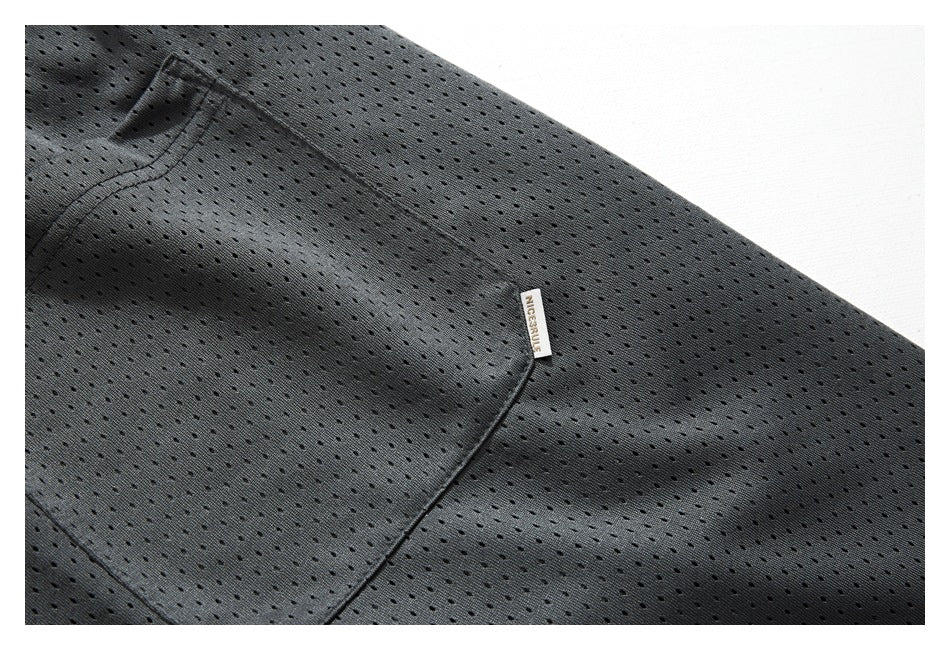 Close-up of a pocket on charcoal perforated shorts, with a small sewn label at the opening.
