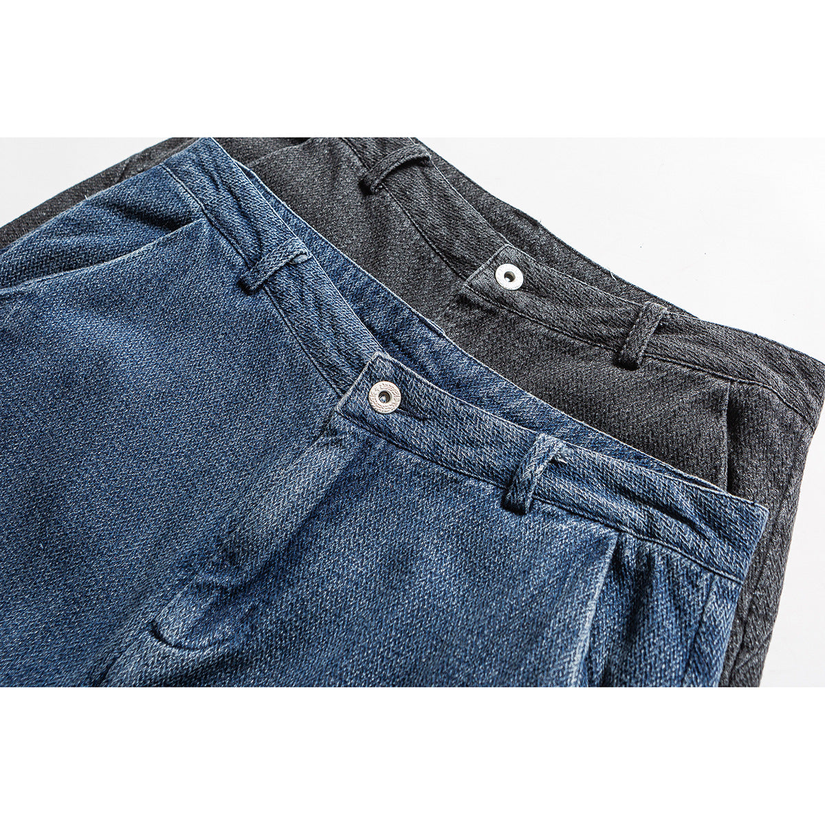 Close-up of blue and charcoal trousers showing the waistbands, belt loops, and metal buttons.