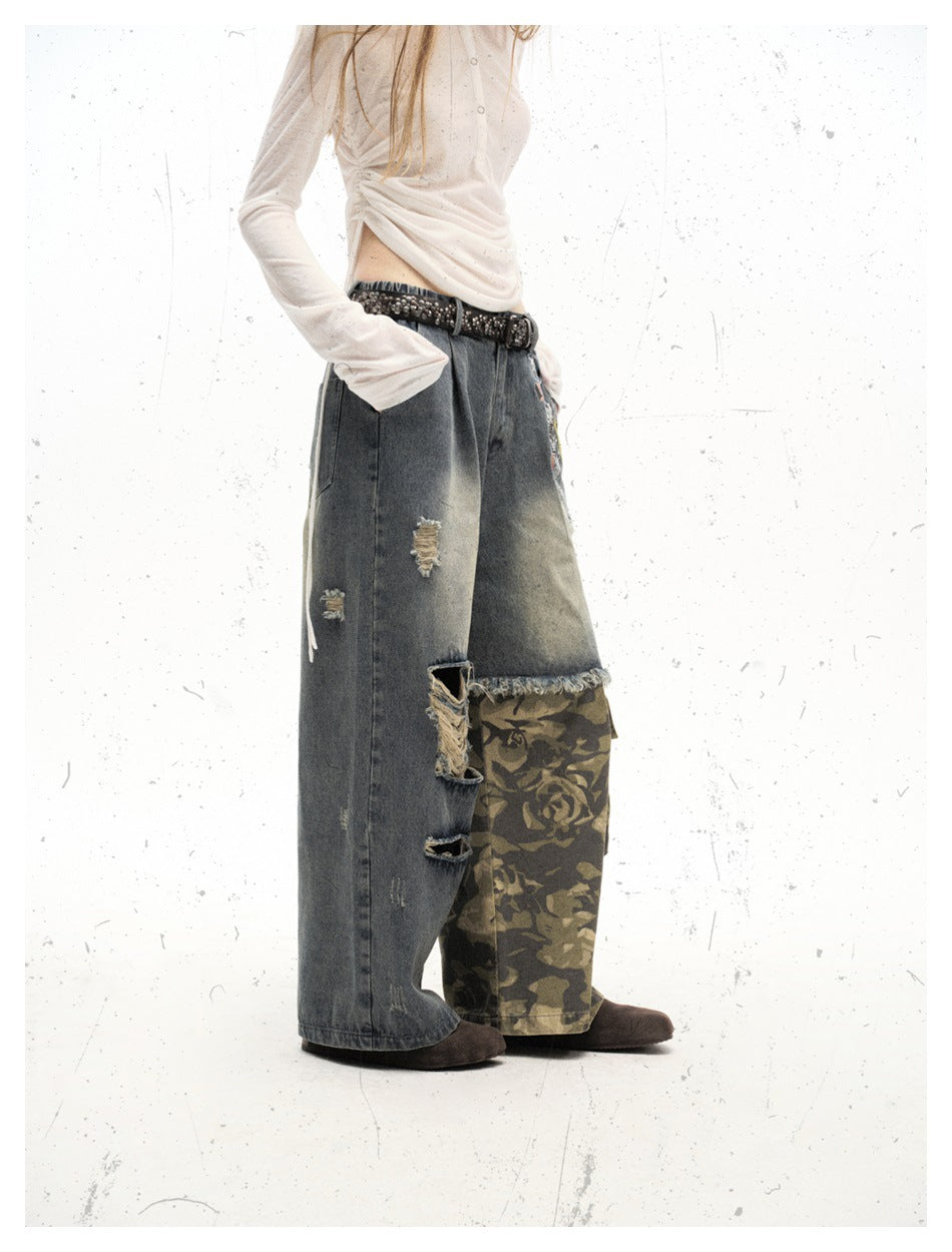 Side view of a model wearing oversized distressed gray denim pants with a frayed hem and olive camouflage cargo panels.