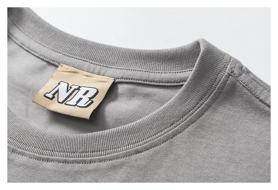 Close-up of a gray T-shirt's ribbed crew neckline and tan NB label.