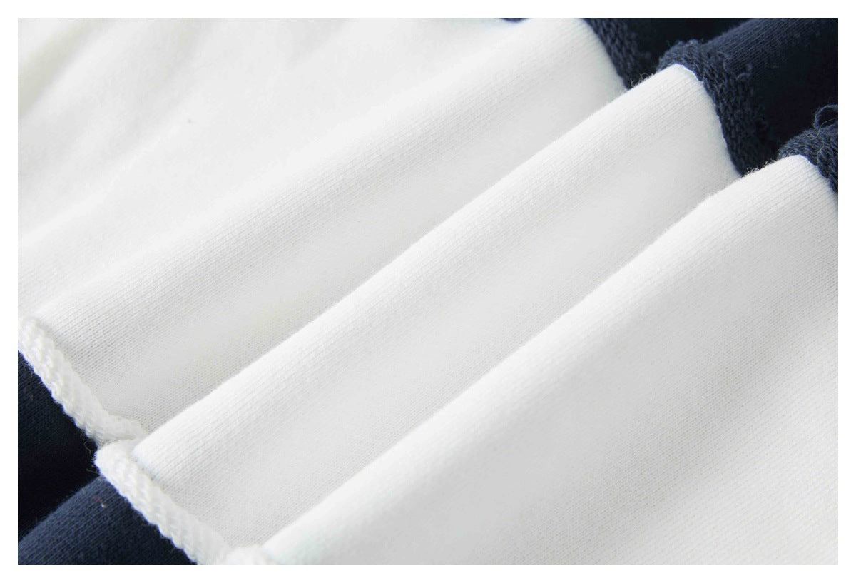 Close-up of folded white garment fabric with a navy edge and visible stitching.
