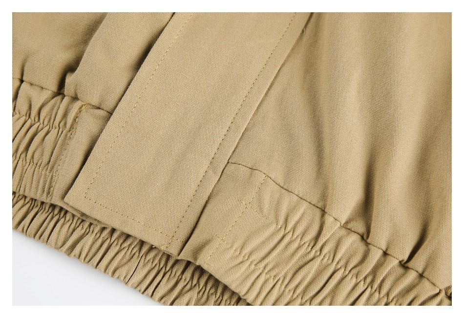 Close-up of a tan garment's gathered elastic edge and stitched fabric tab.