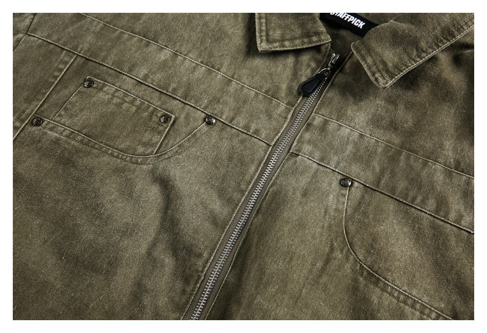 Close-up of an olive-brown jacket front with a metal zipper and multiple buttoned pockets.