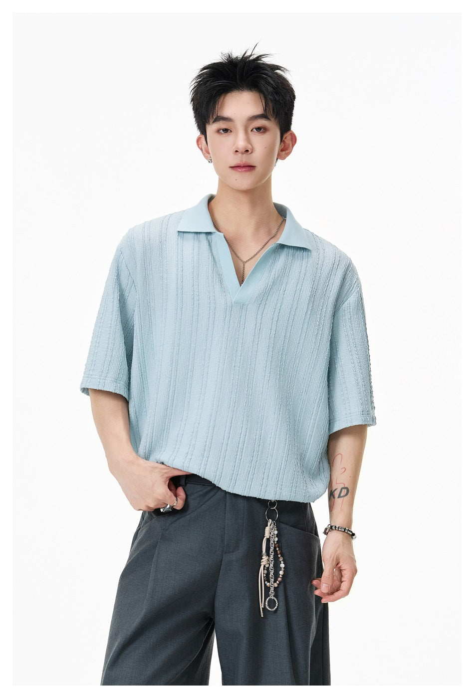 Model wearing a pale blue textured short-sleeve polo with dark trousers.
