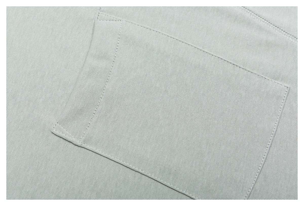 Close-up of a rectangular stitched pocket on pale sage-gray knit fabric.
