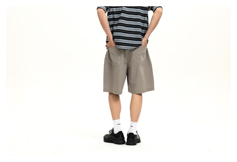 Cropped rear view of a model wearing light gray shorts with a striped shirt and black shoes.