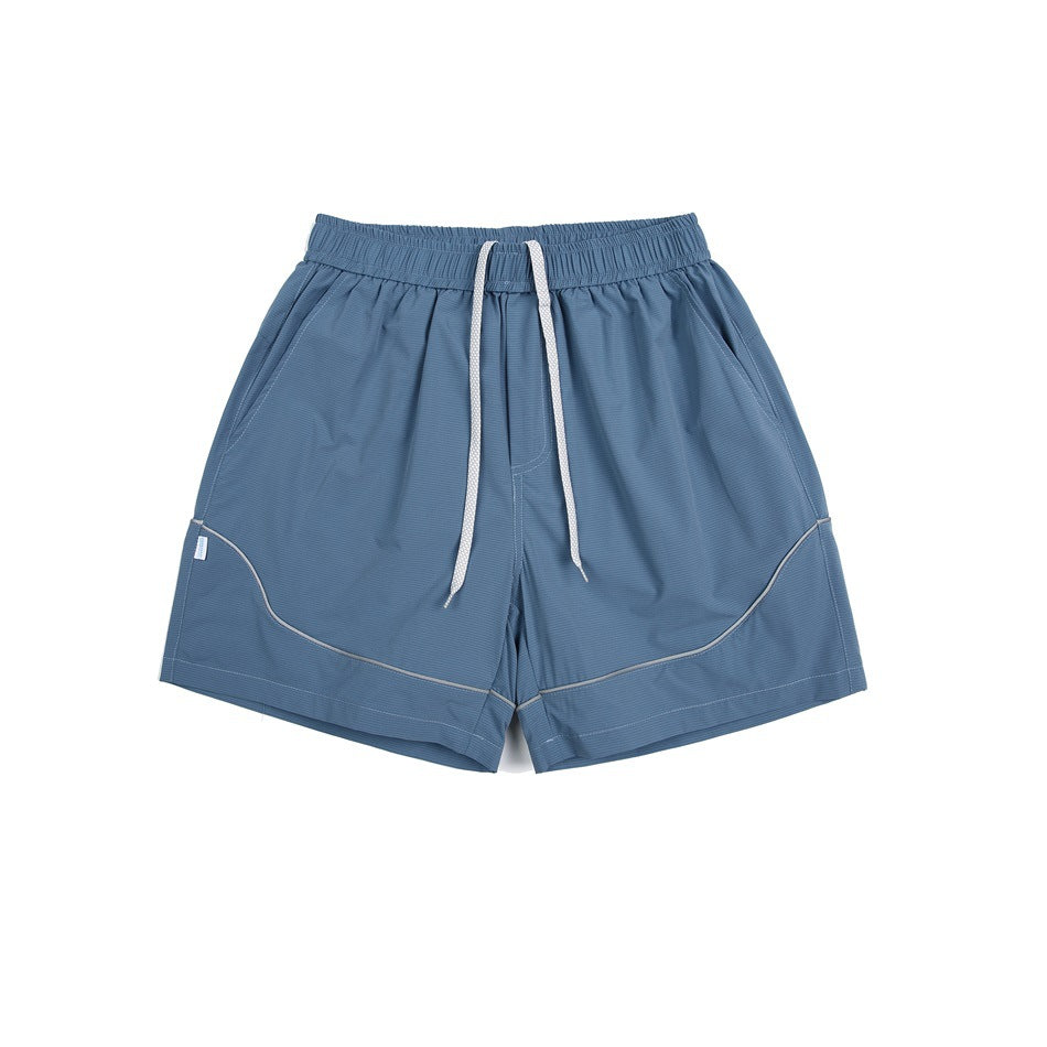 Blue elastic-waist shorts with white drawstring, side pockets and curved gray piping, flat lay front view