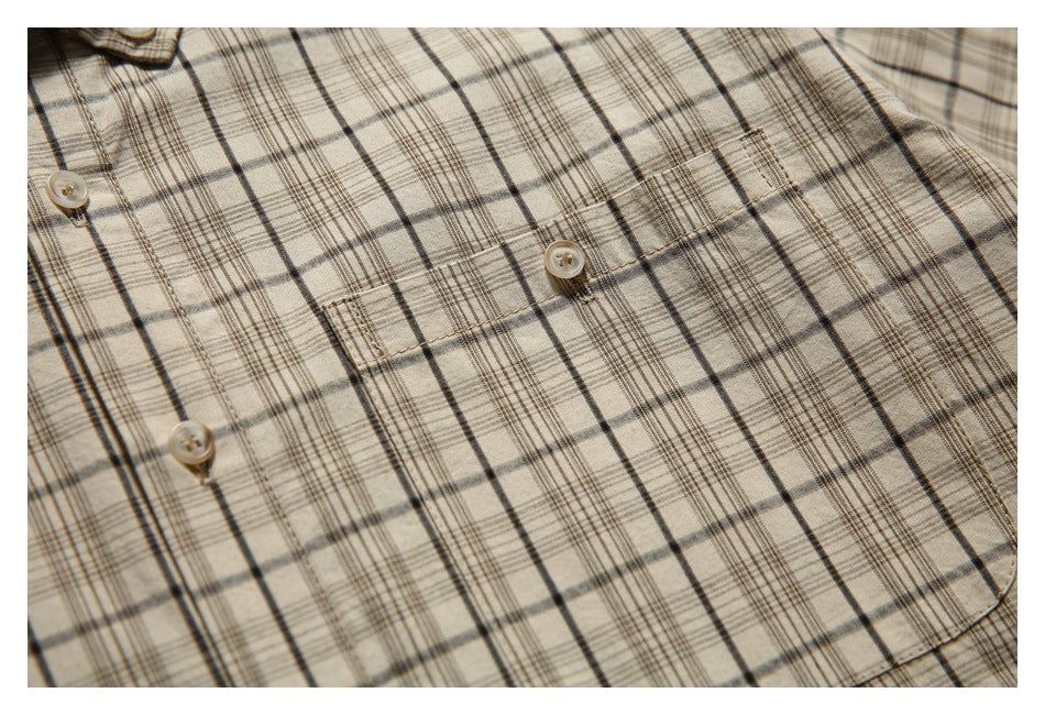 Close-up of a beige plaid shirt front showing its button placket and chest pocket.