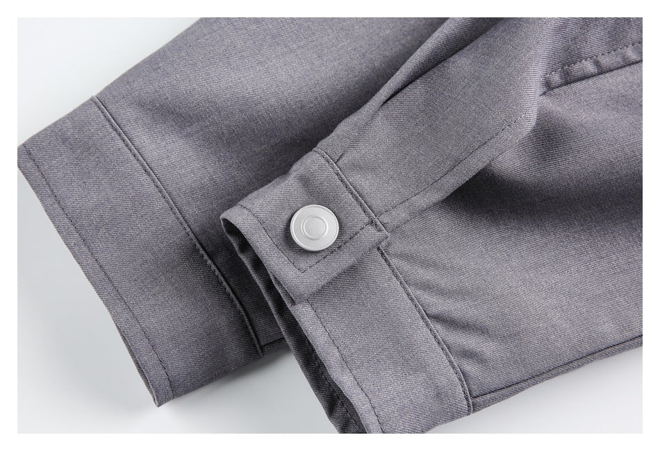 Close-up of gray garment cuff with a round silver snap and visible stitching.