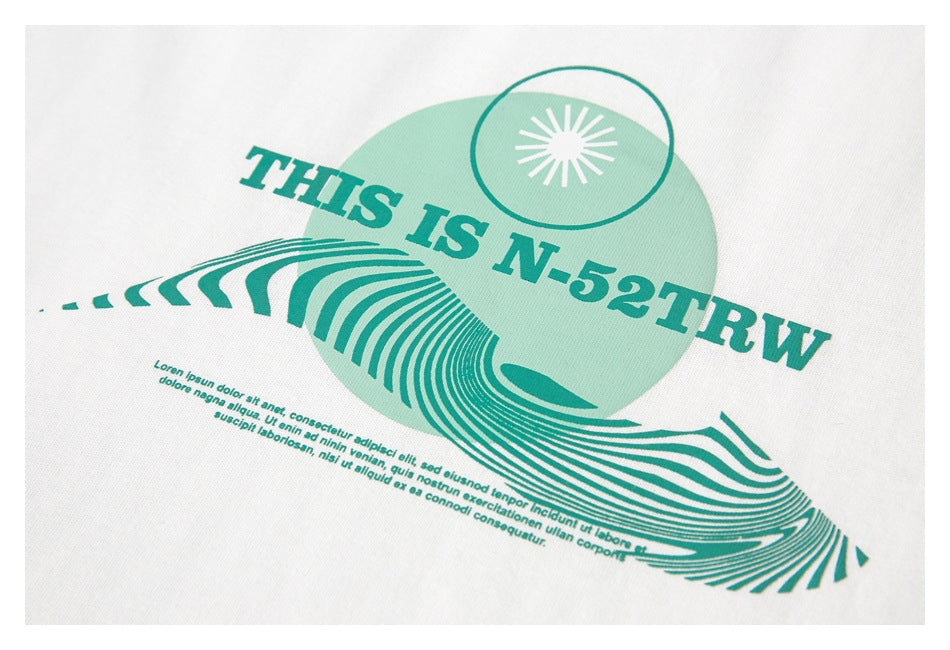 Close-up of a mint-green graphic with lettering and a radiating motif printed on white fabric.