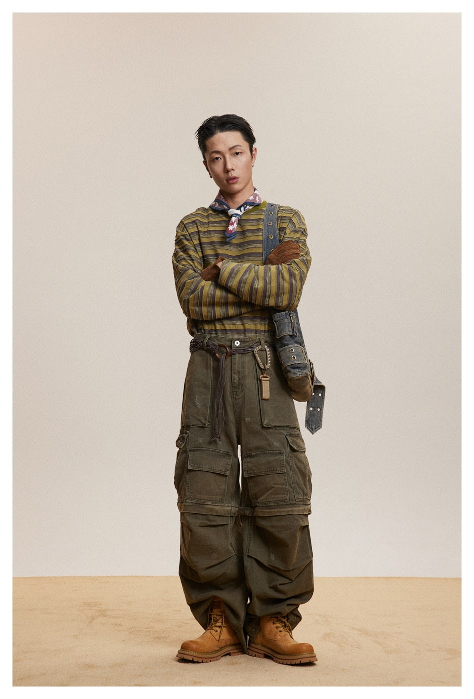 Model wearing green striped long-sleeve top with olive cargo pants, neckerchief and tan boots, arms crossed