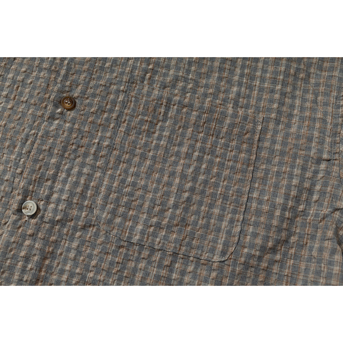 Close-up of a gray-brown plaid shirt's chest pocket and buttons.