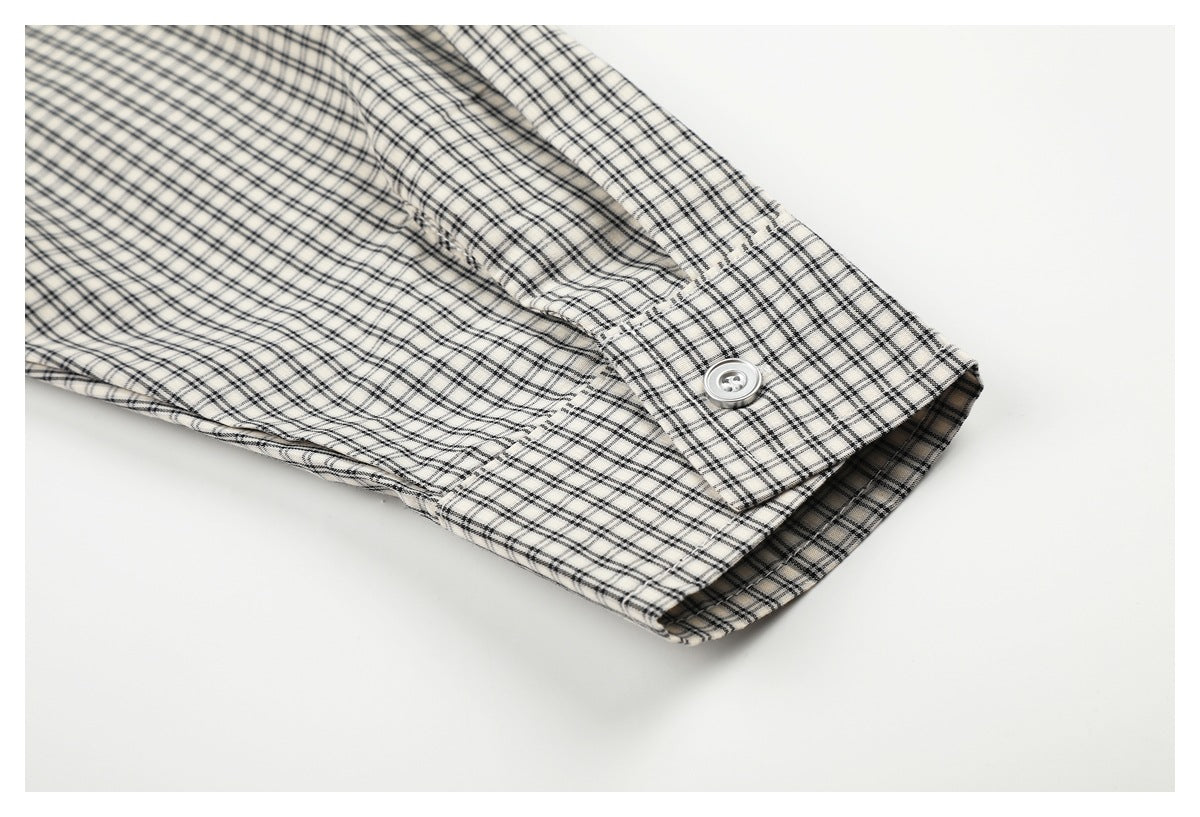 Close-up of the cream-and-black plaid shirt cuff, showing its button and stitched edge.