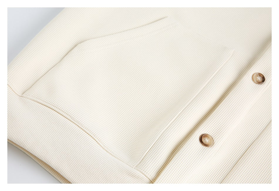 Close-up showing the cream knit top's chest pocket and button placket.