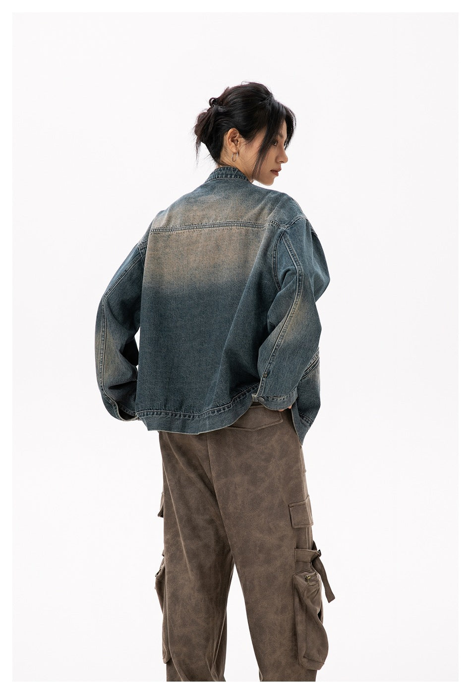 Back view of a model wearing the blue washed denim jacket with faded tan patch across the upper back