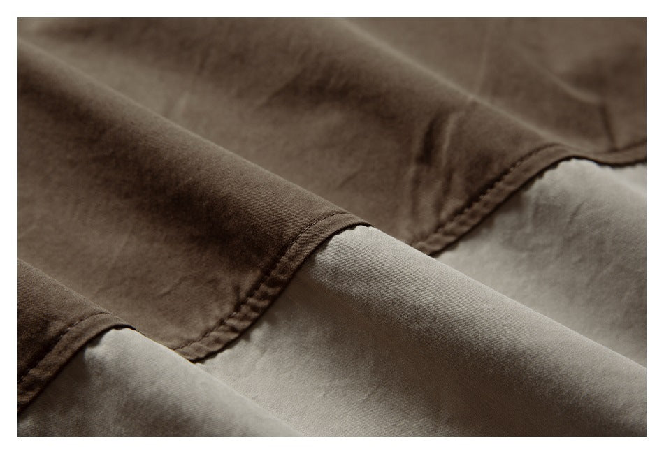 Close-up of stitched seams and overlapping folds in brown fabric.