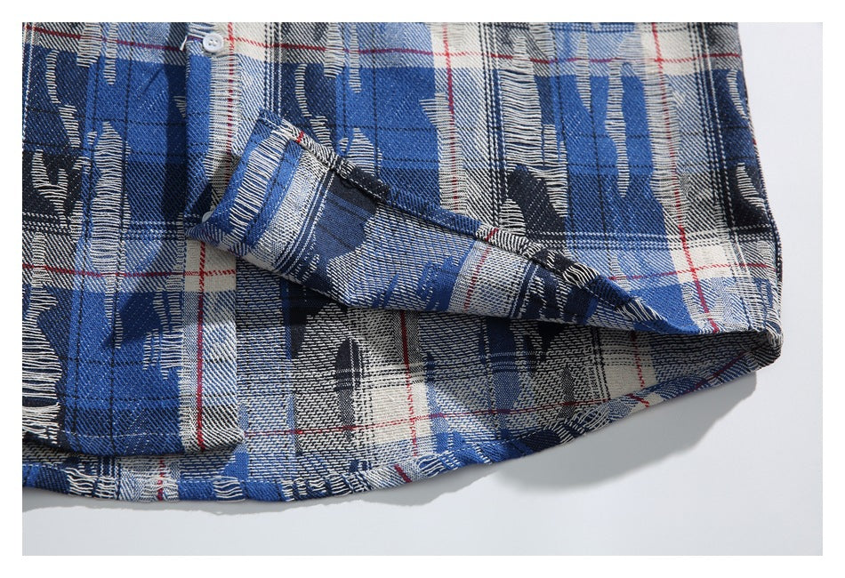 Close-up of the plaid shirt's lower front and hem, with a button and folded fabric edge.